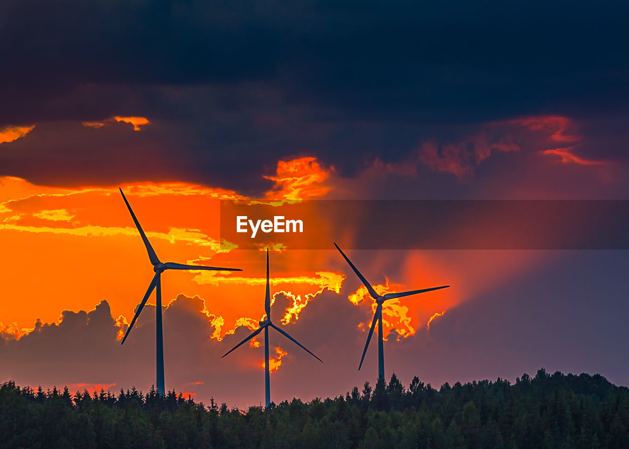 SILHOUETTE OF WIND TURBINES ON FIELD DURING SUNSET