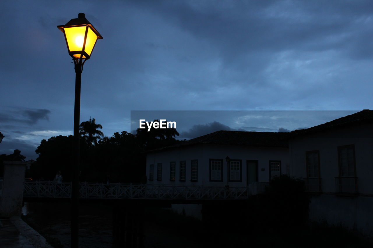 LOW ANGLE VIEW OF ILLUMINATED STREET LIGHTS AGAINST SKY