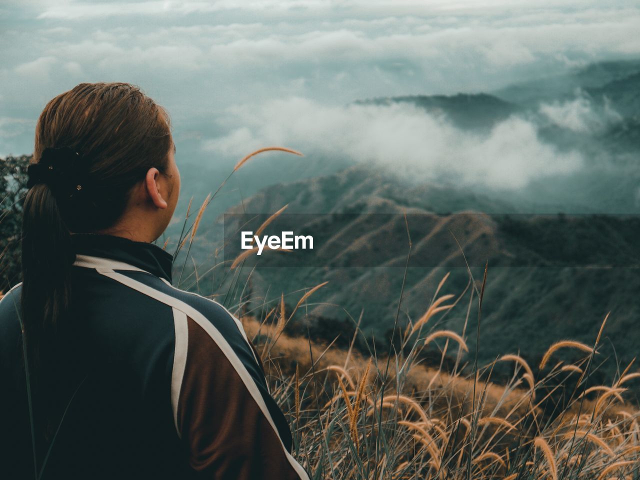 Rear view of woman standing on mountain against sky