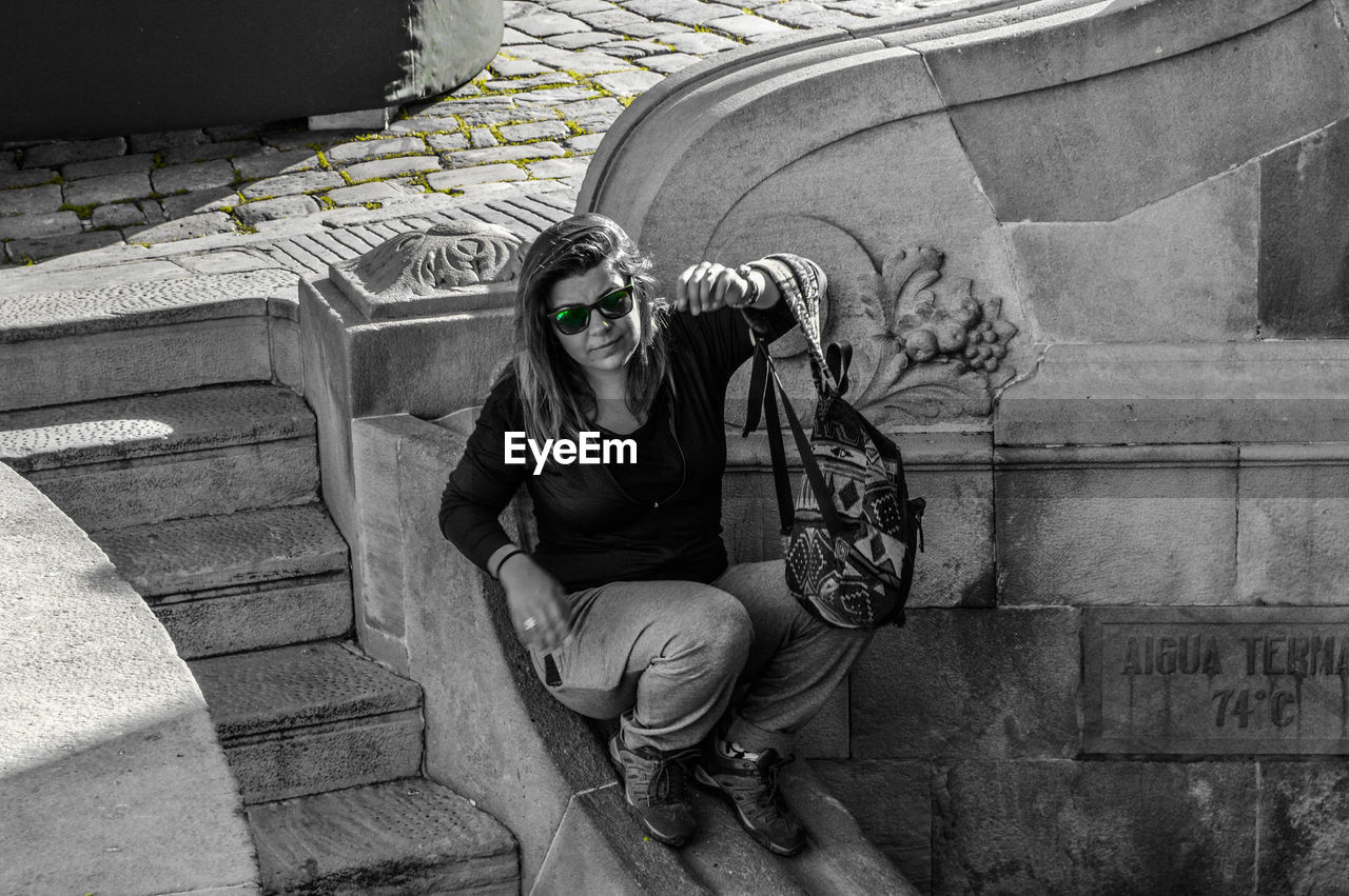 Young woman sitting on railing by steps