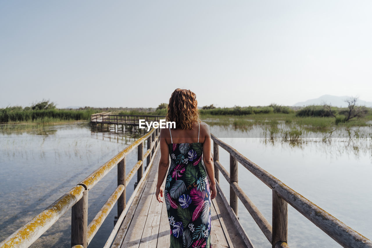 Woman standing on footbridge over lake