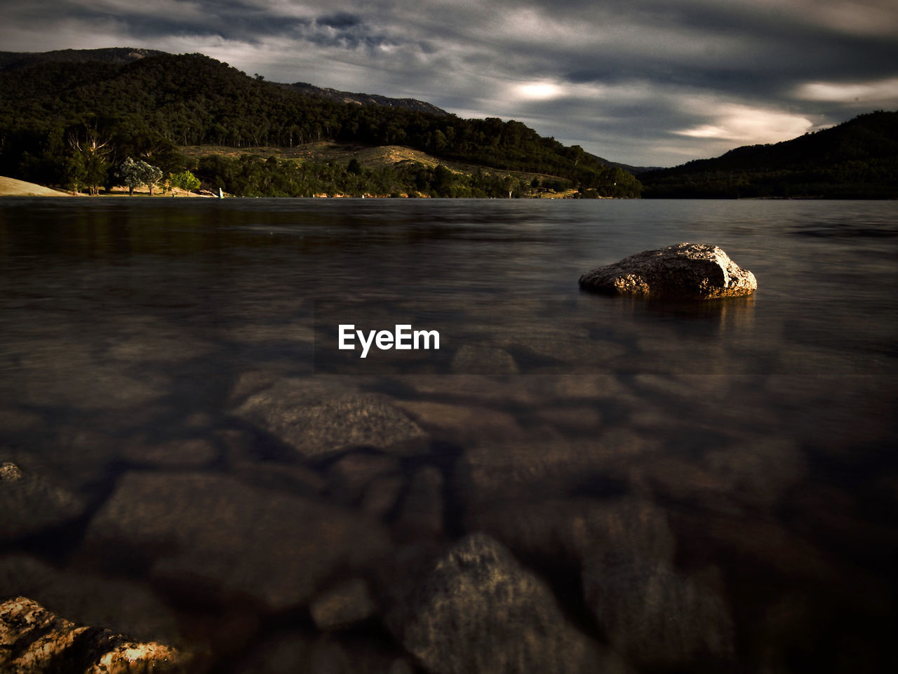 Scenic view of sea by mountain against sky