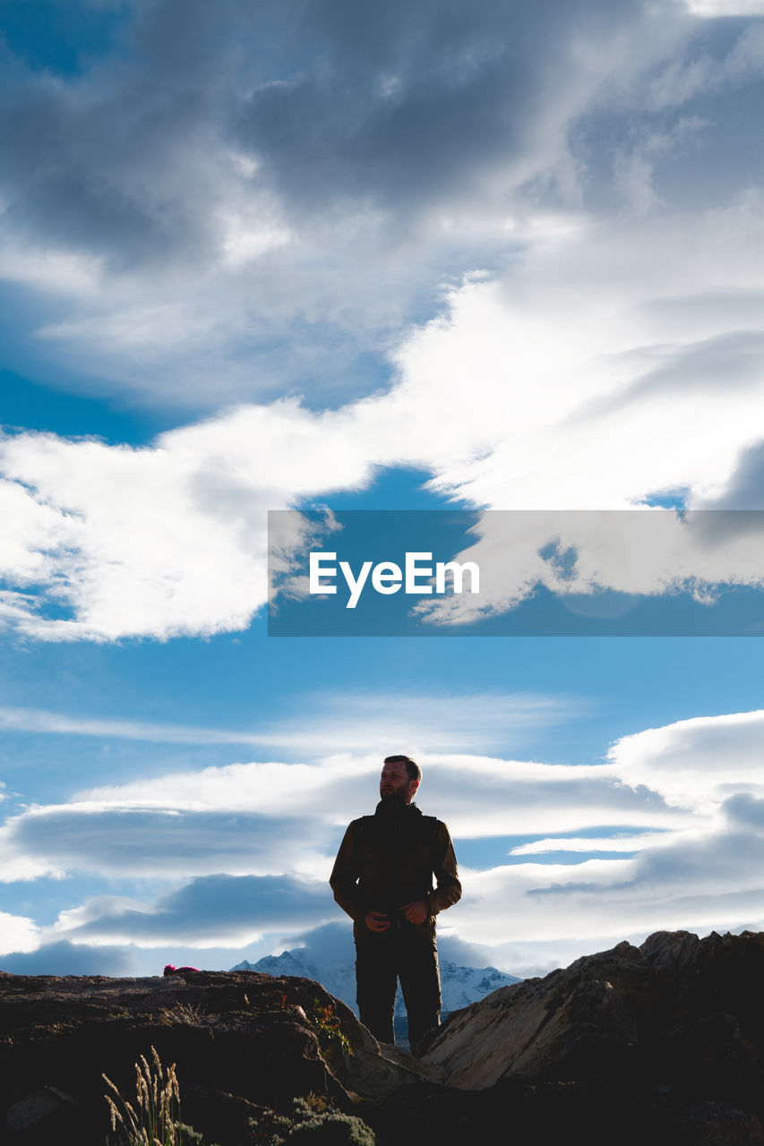 Man standing on rock against sky