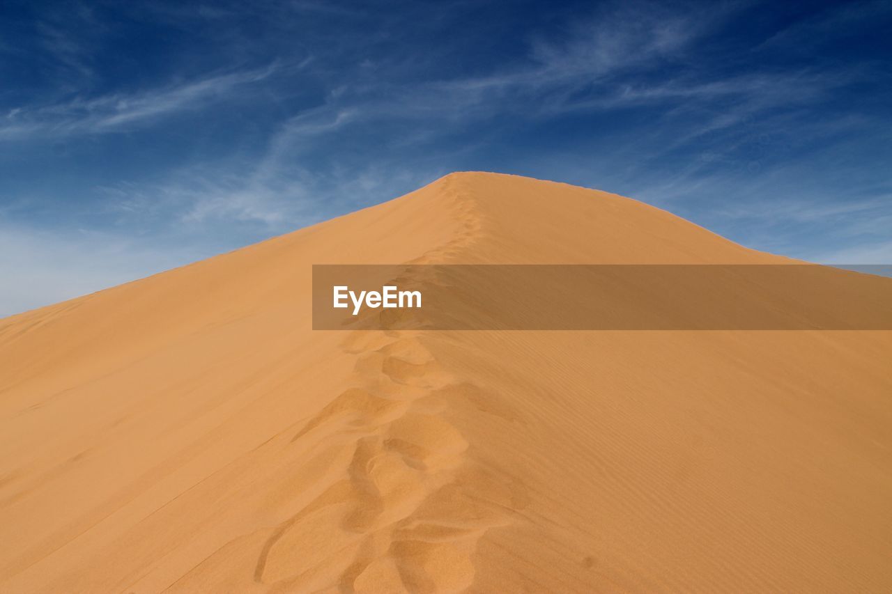 Sand dunes at desert against sky