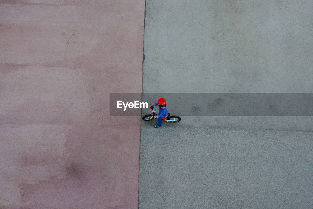 High angle view of boy with bicycle on footpath