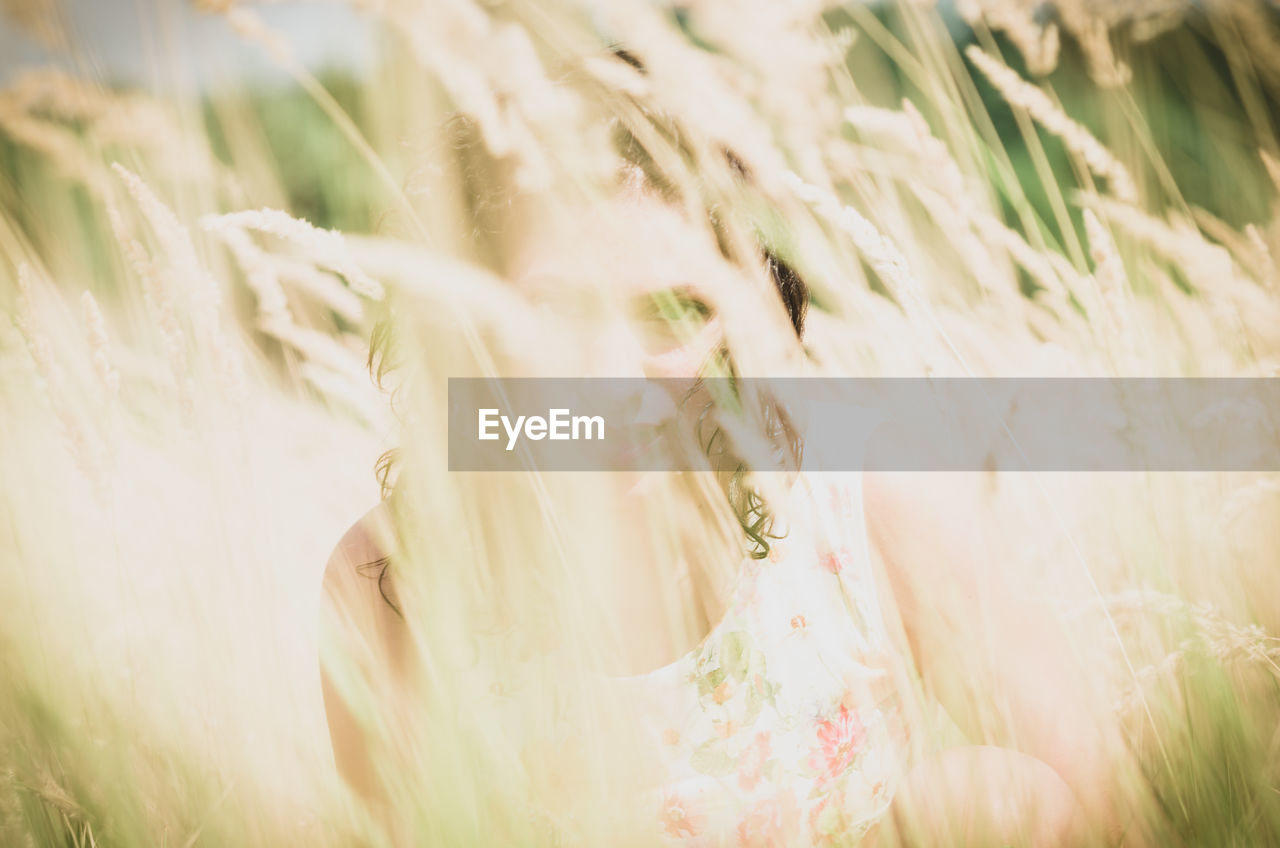 Portrait of young woman amidst grass on field