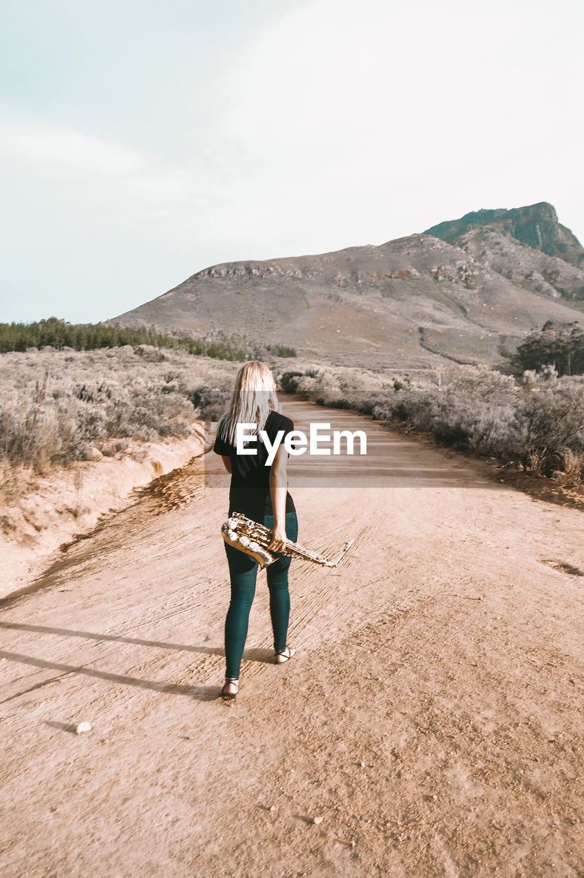 Full length rear view of woman on arid landscape