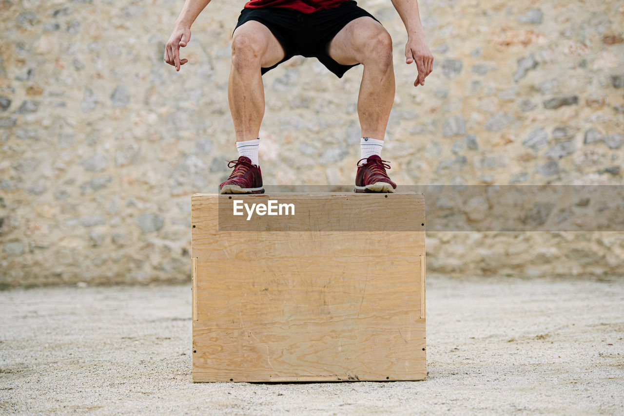 Man practicing crossfit jumping into a plyometric box.
