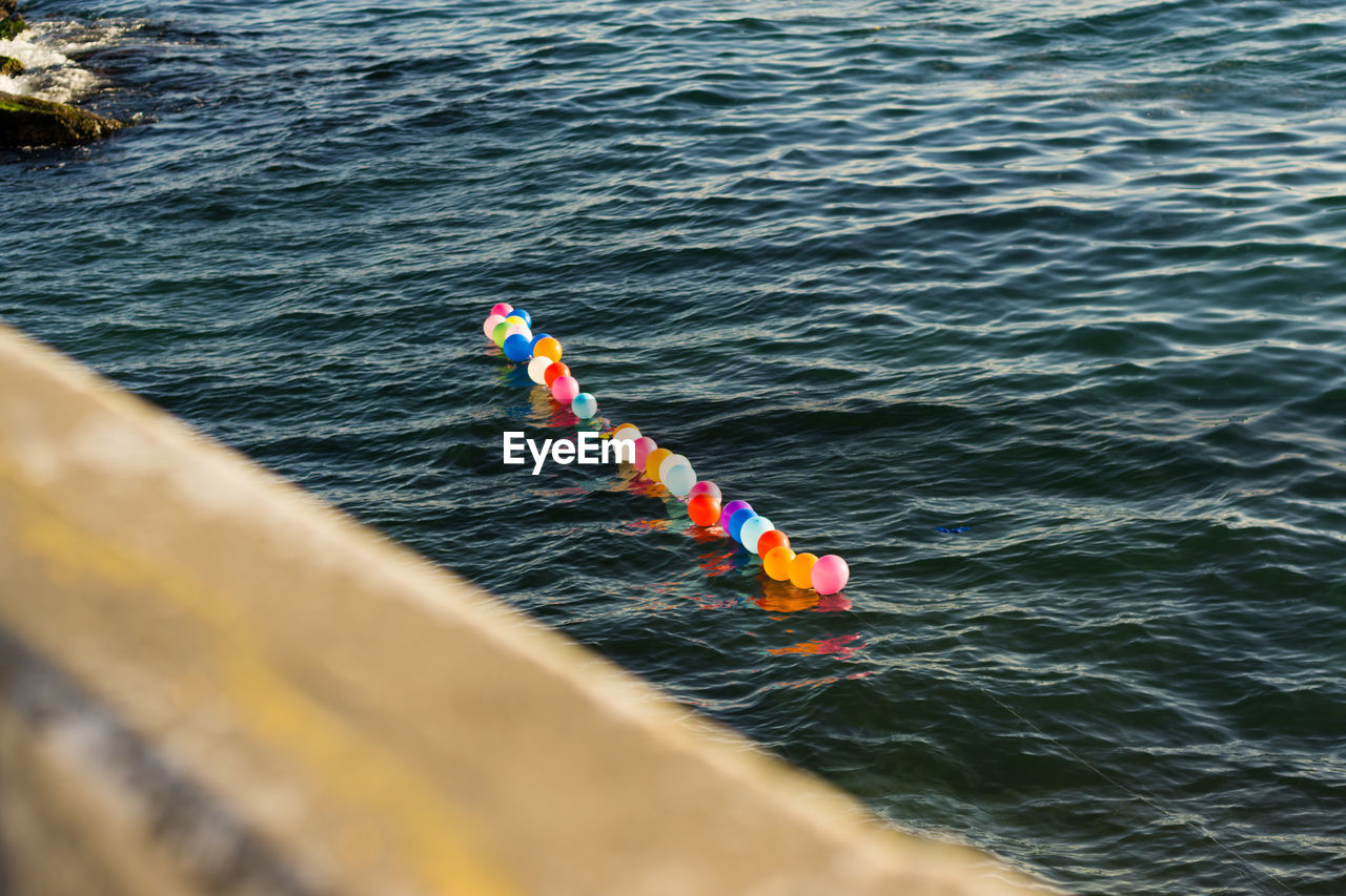 High angle view of multi colored balloons floating in sea