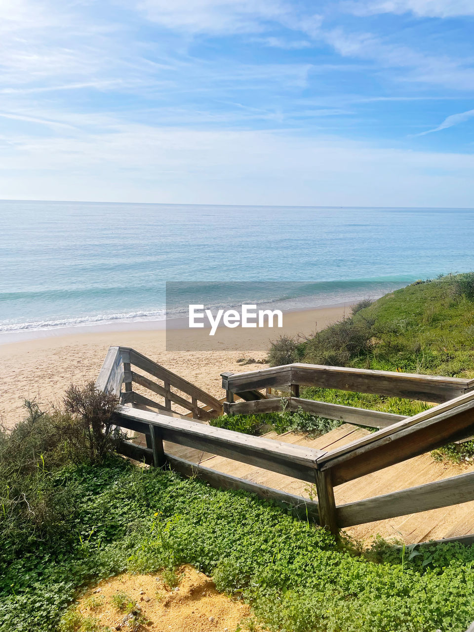 sea, water, land, beach, horizon over water, sky, horizon, nature, scenics - nature, shore, beauty in nature, tranquility, tranquil scene, plant, vacation, day, grass, coast, no people, ocean, idyllic, sand, walkway, cloud, seat, outdoors, sunlight, non-urban scene, body of water, bay, green, bench, high angle view, railing, wood