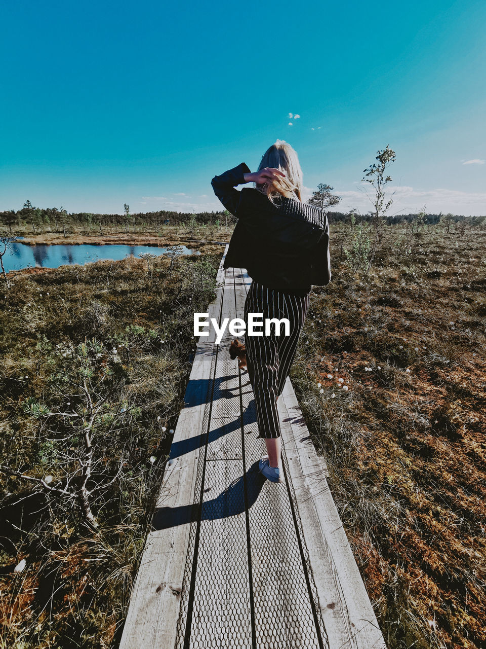REAR VIEW OF WOMAN STANDING ON WALKWAY