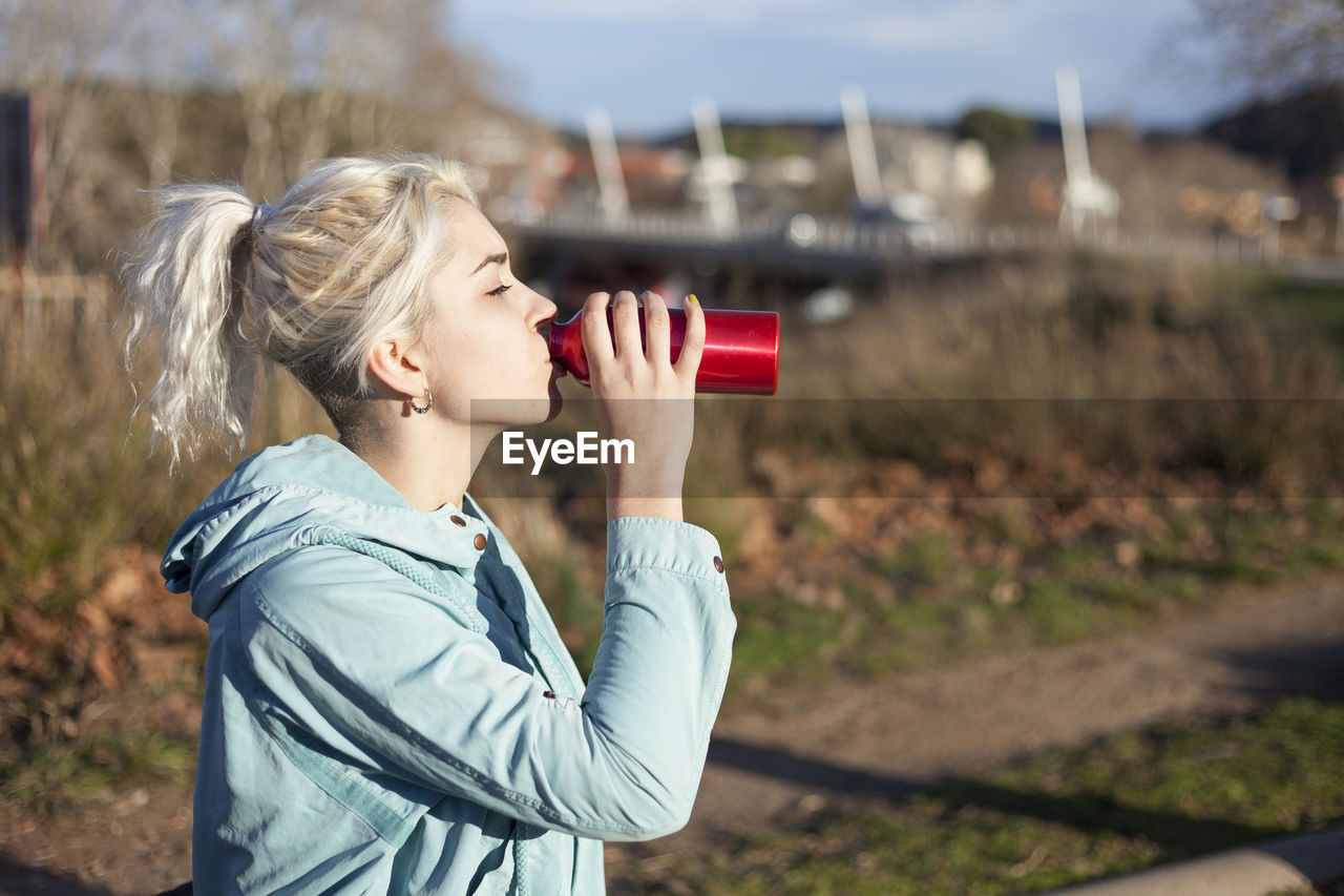 Woman drinking water from bottle in sunny day