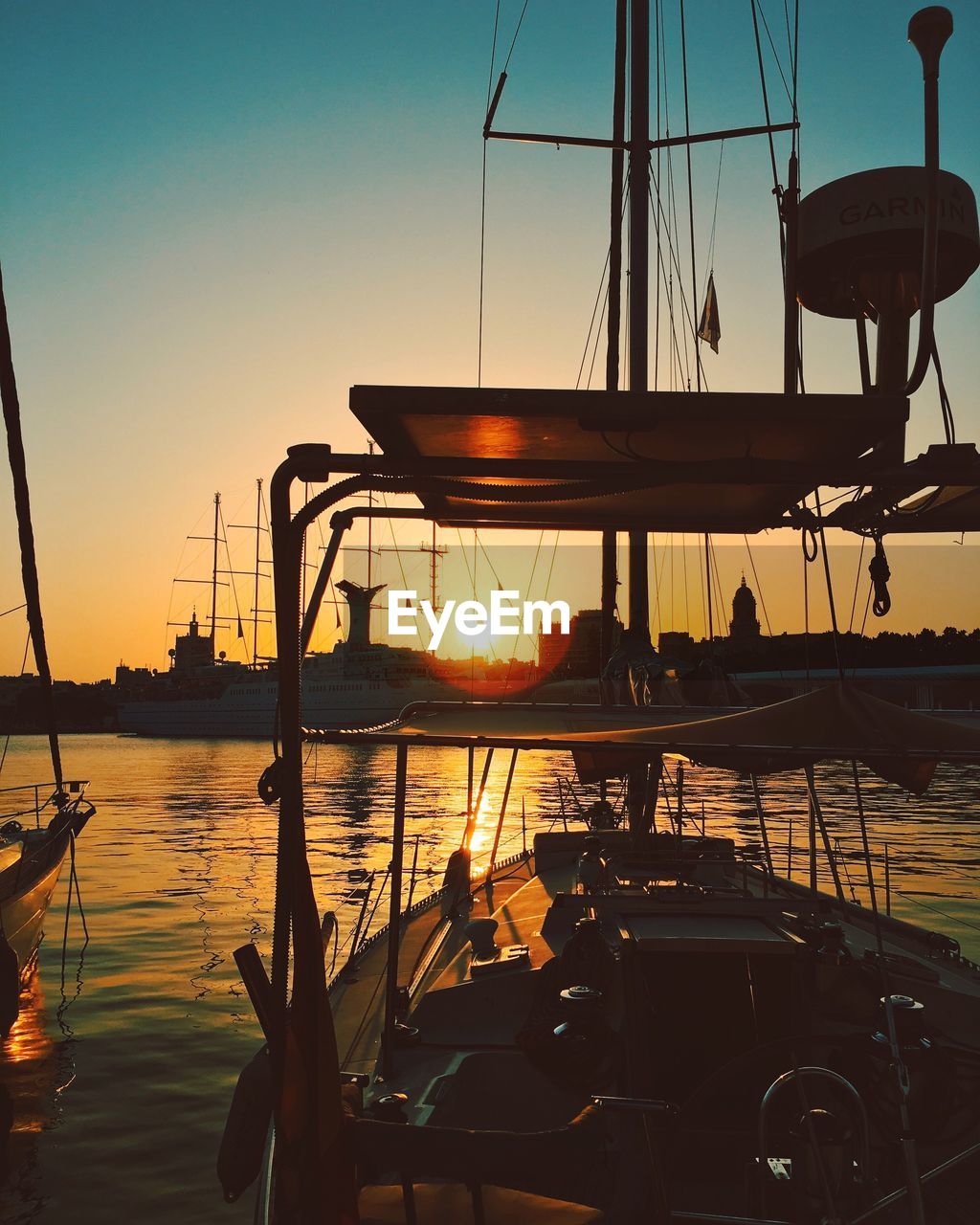 SILHOUETTE BOATS SAILING IN SEA AT SUNSET