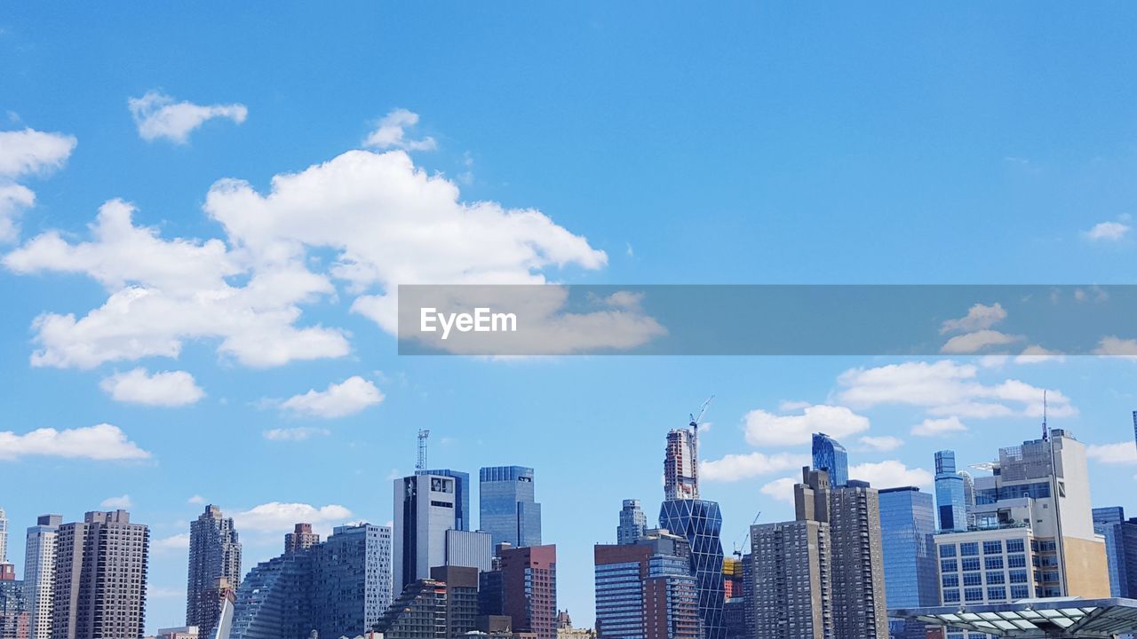 Low angle view of skyscrapers against cloudy sky