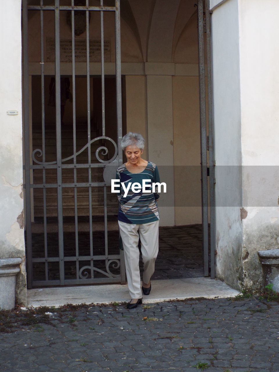 Woman walking against metal gate