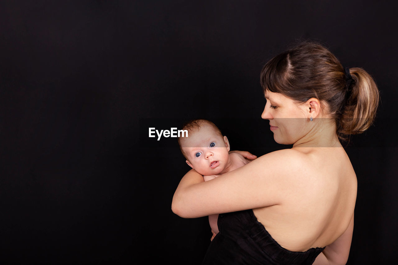 Mother holding son against black background