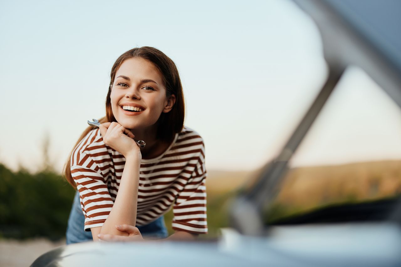 portrait of young woman sitting against car