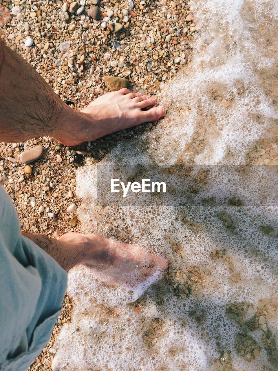 Low section of man standing at beach