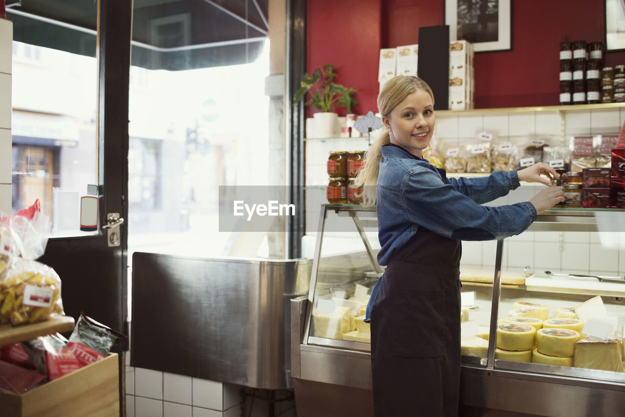 Side view portrait of confident saleswoman standing working in supermarket