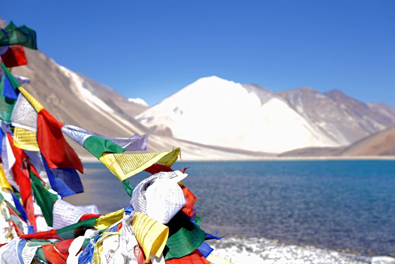 VARIOUS FLAGS ON MOUNTAIN AGAINST CLEAR BLUE SKY