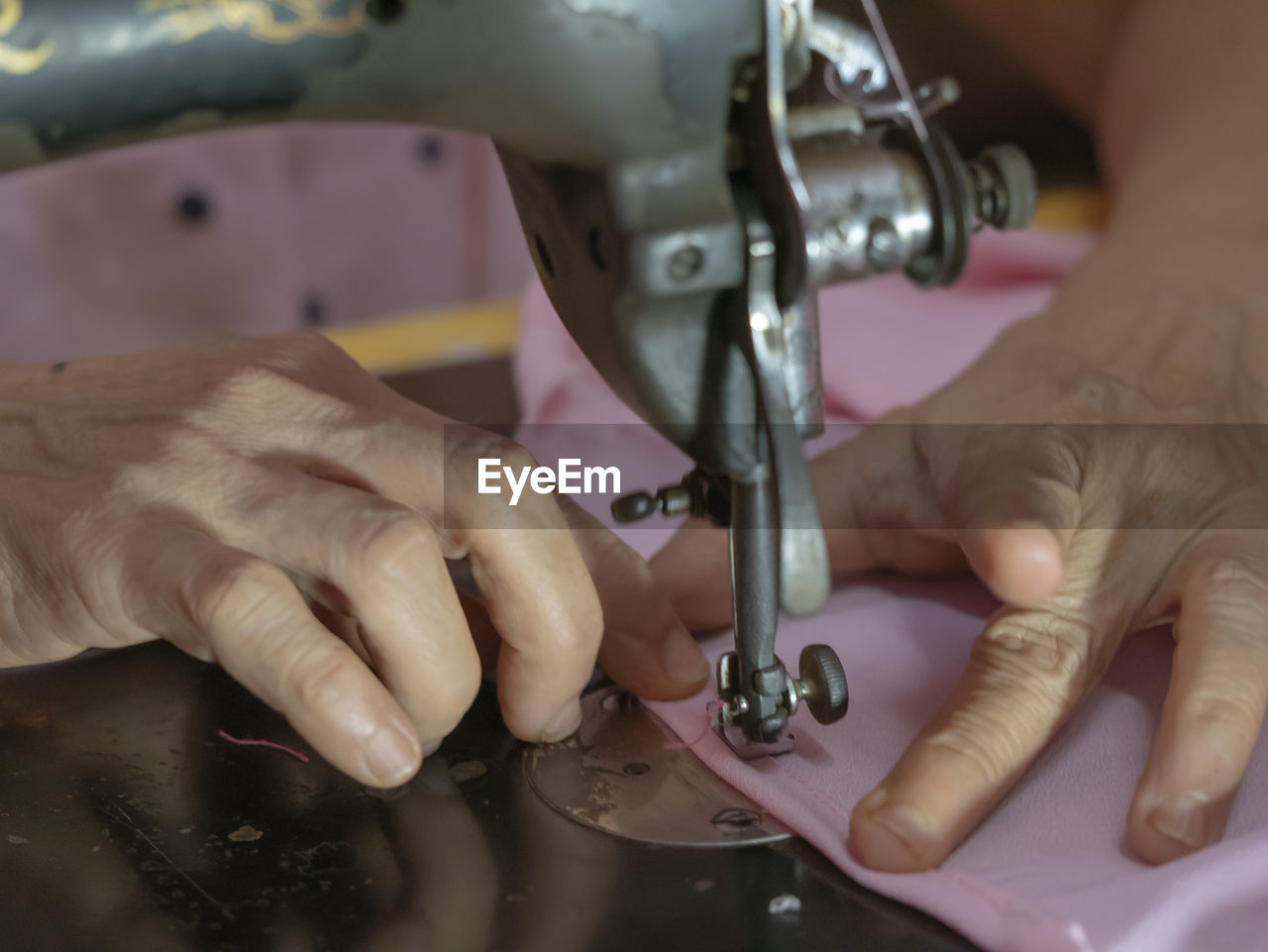 Close-up of woman sewing textile using machine