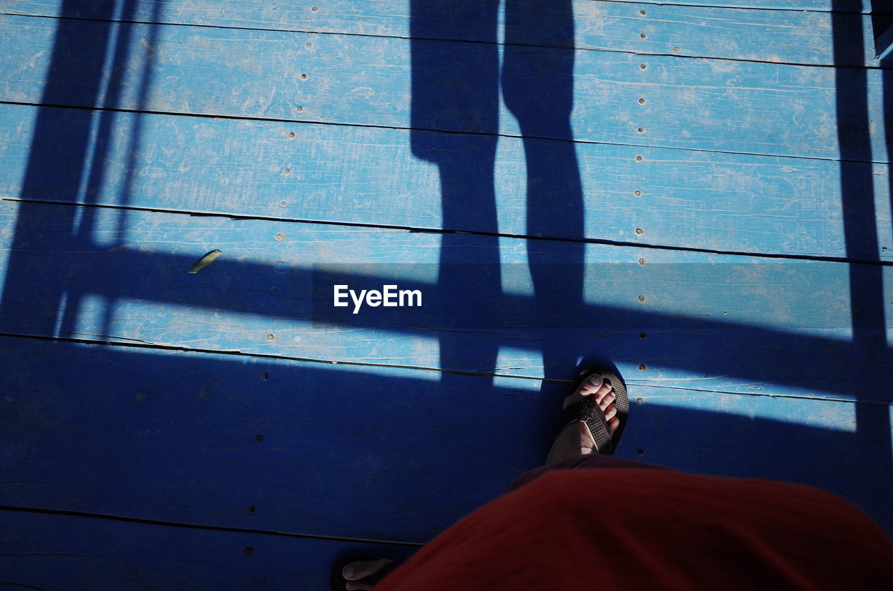 LOW SECTION OF PEOPLE STANDING BY SHADOW ON FLOOR