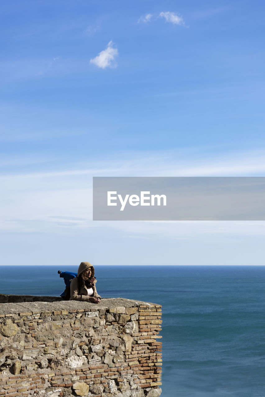 Girl by the sea against sky