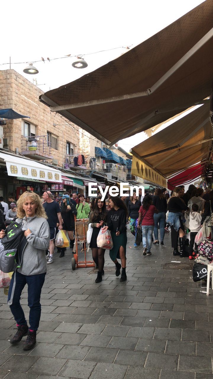 PEOPLE WALKING IN MARKET AGAINST SKY