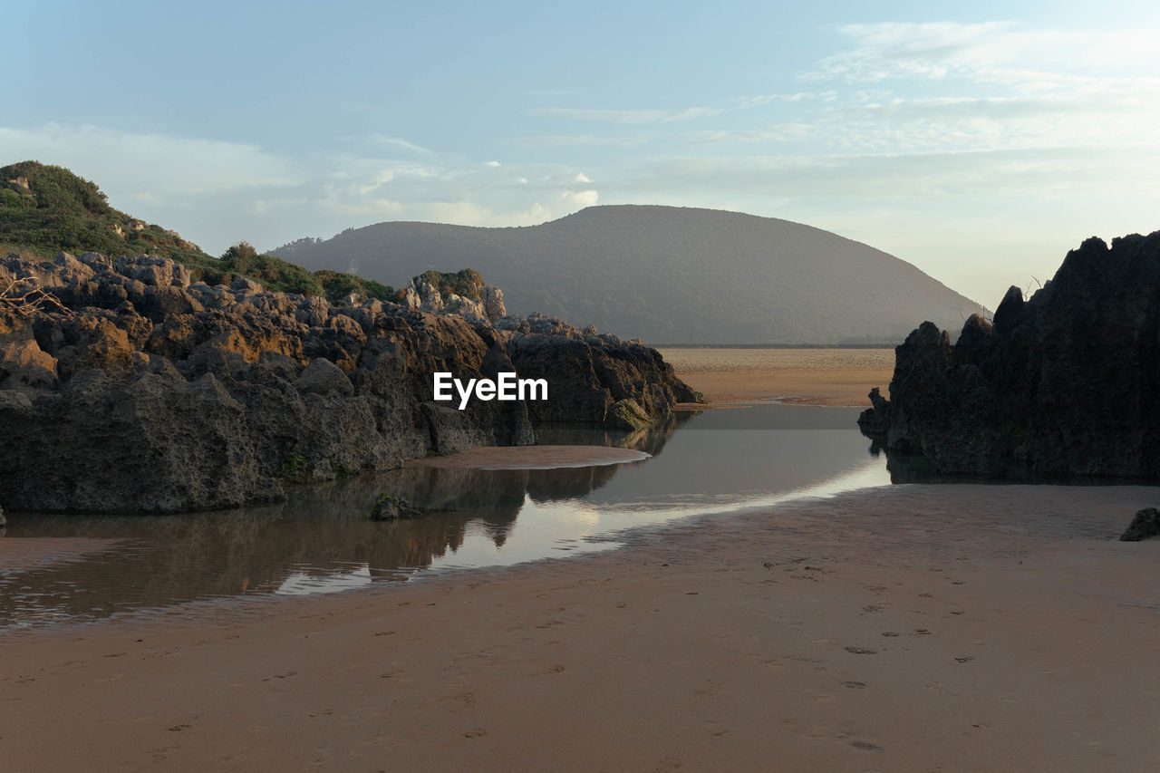 water, land, sky, body of water, beach, sea, coast, scenics - nature, nature, shore, beauty in nature, bay, environment, landscape, sand, rock, mountain, tranquility, no people, travel destinations, travel, ocean, cloud, coastline, tranquil scene, outdoors, sunset, non-urban scene, tourism, terrain, cliff, natural environment