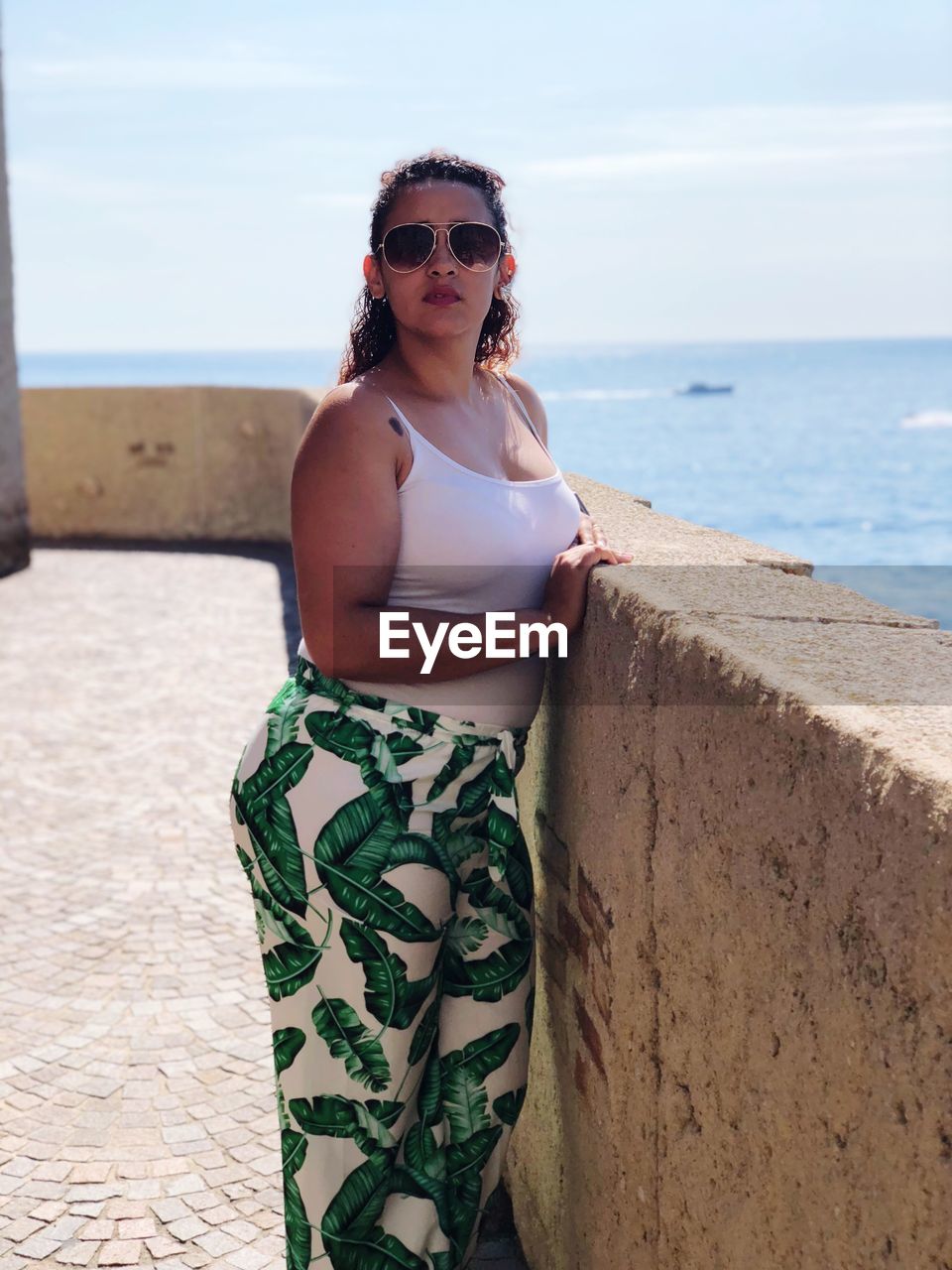 Portrait of young woman wearing sunglasses while standing on promenade