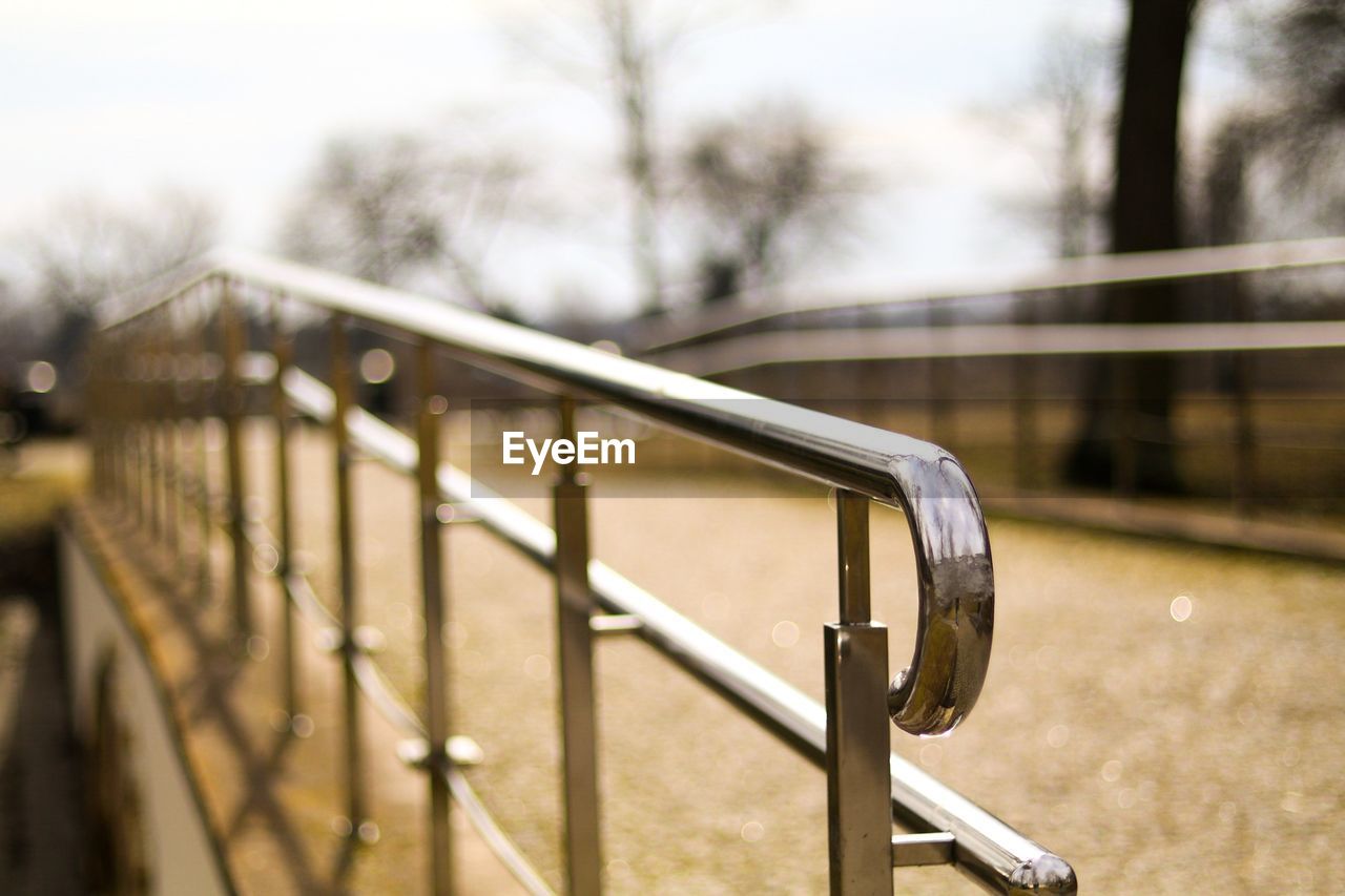 CLOSE-UP OF METAL RAILING AGAINST TREES