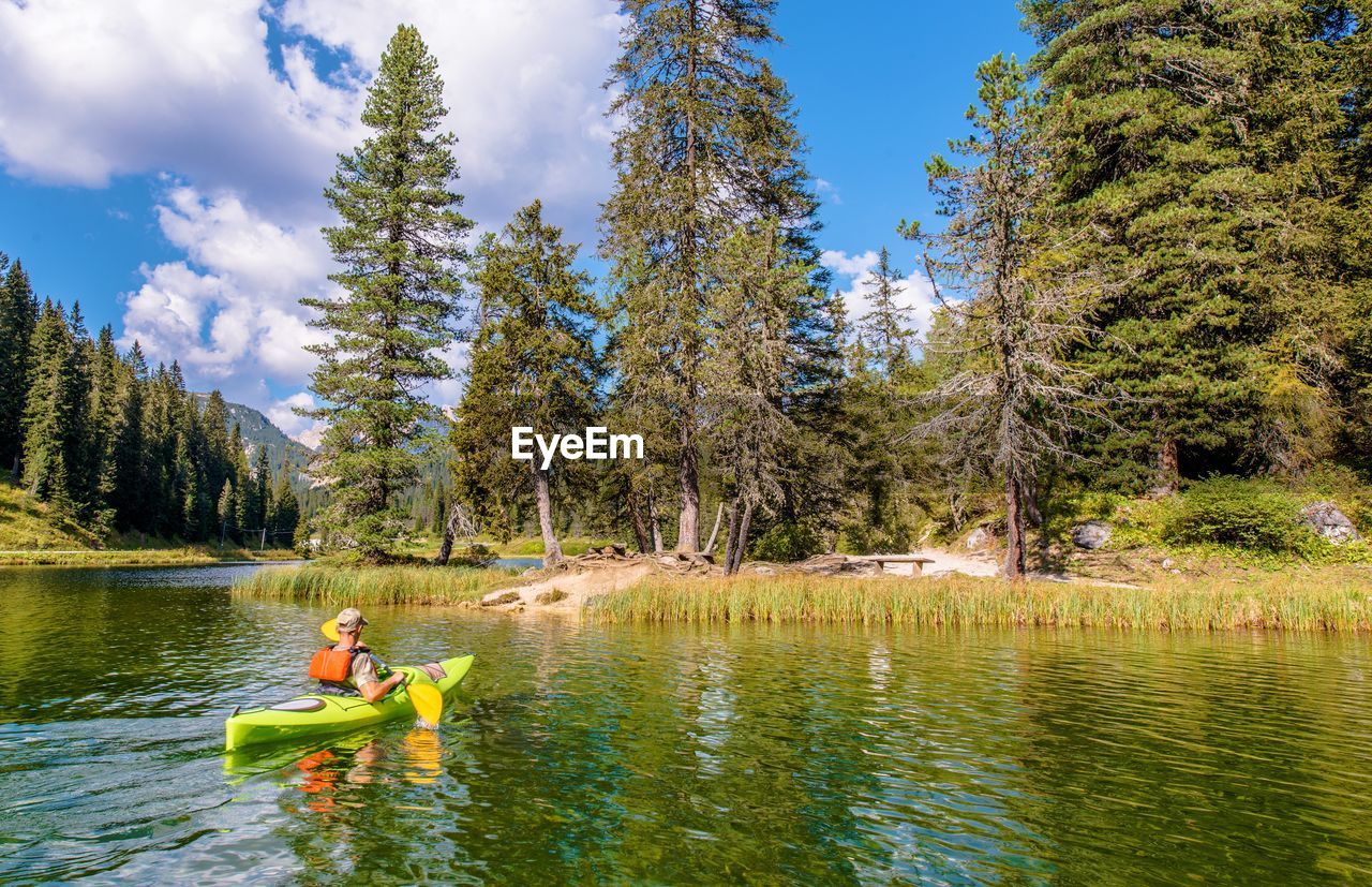 Man kayaking in lake against trees at forest