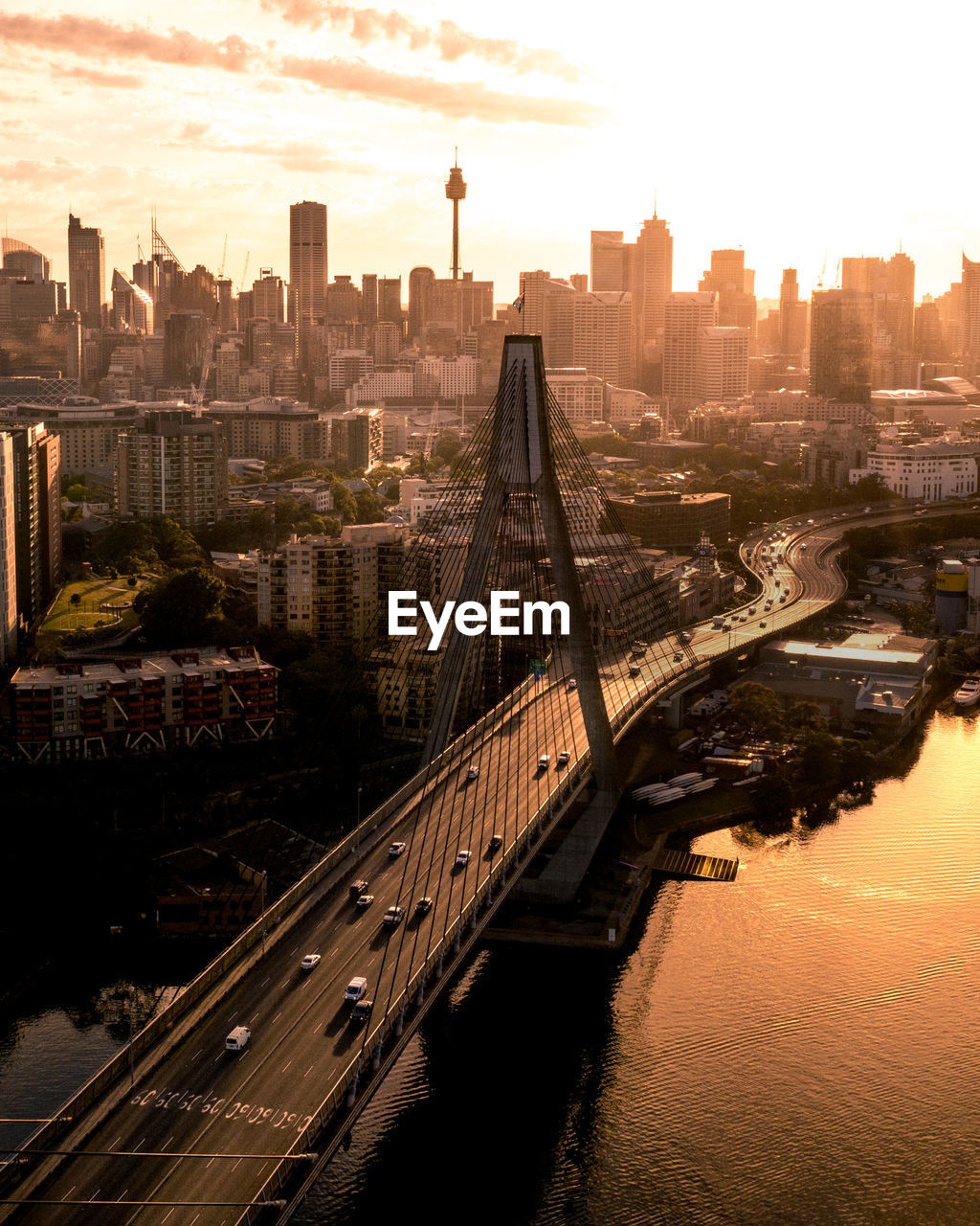 Aerial view of bridge over river against buildings in city during sunset