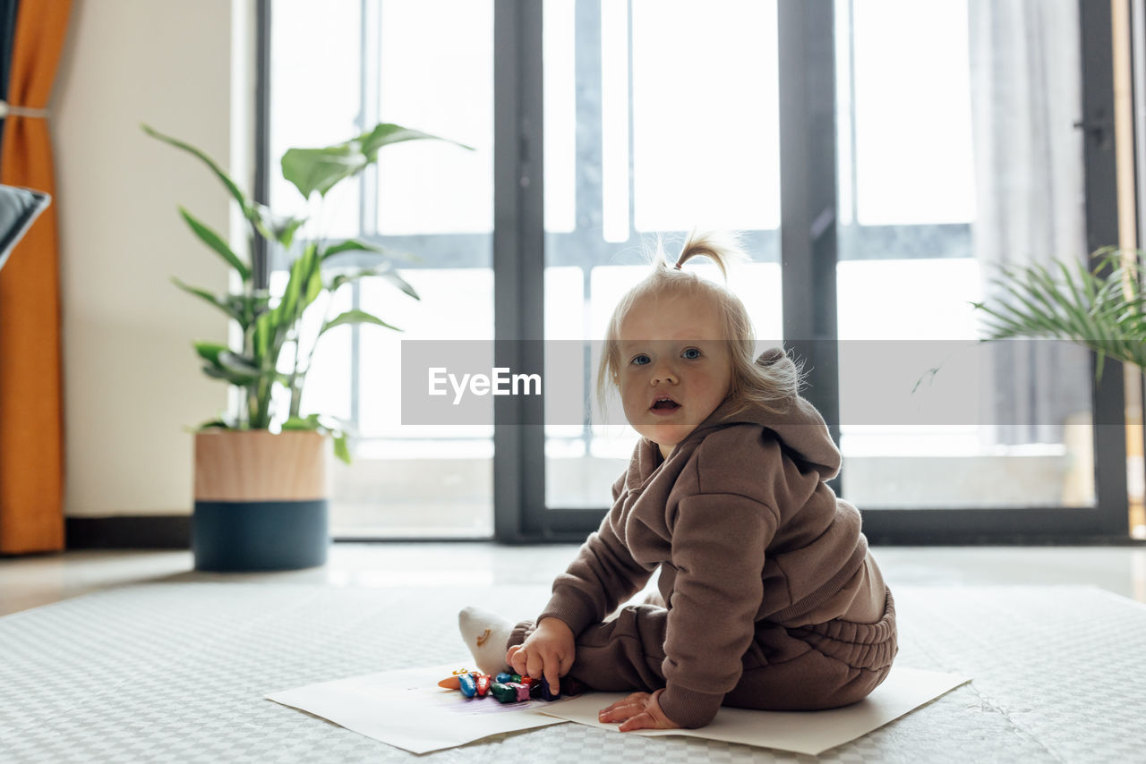 portrait of cute baby boy sitting on floor at home