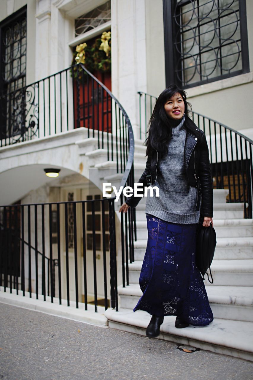 FULL LENGTH PORTRAIT OF WOMAN STANDING ON RAILING