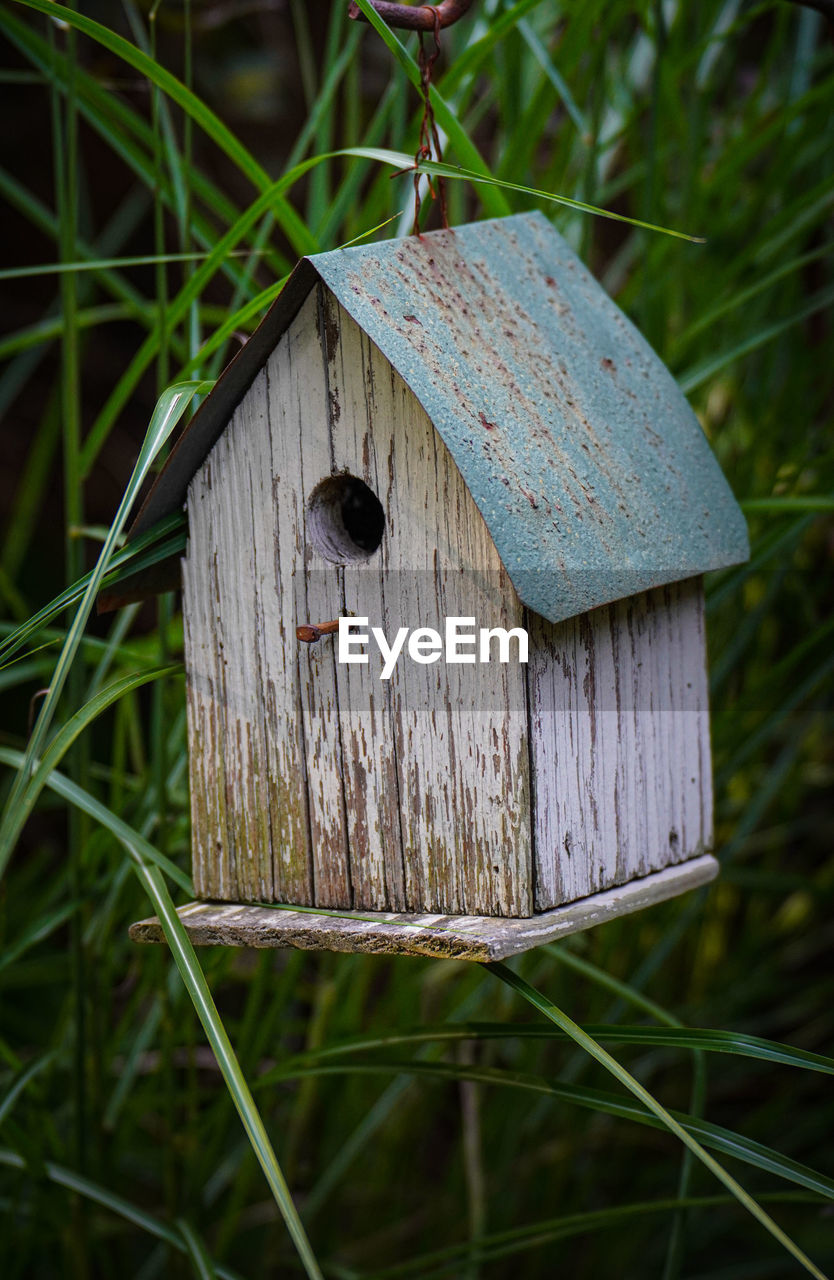 CLOSE-UP OF BIRDHOUSE ON WOODEN POST