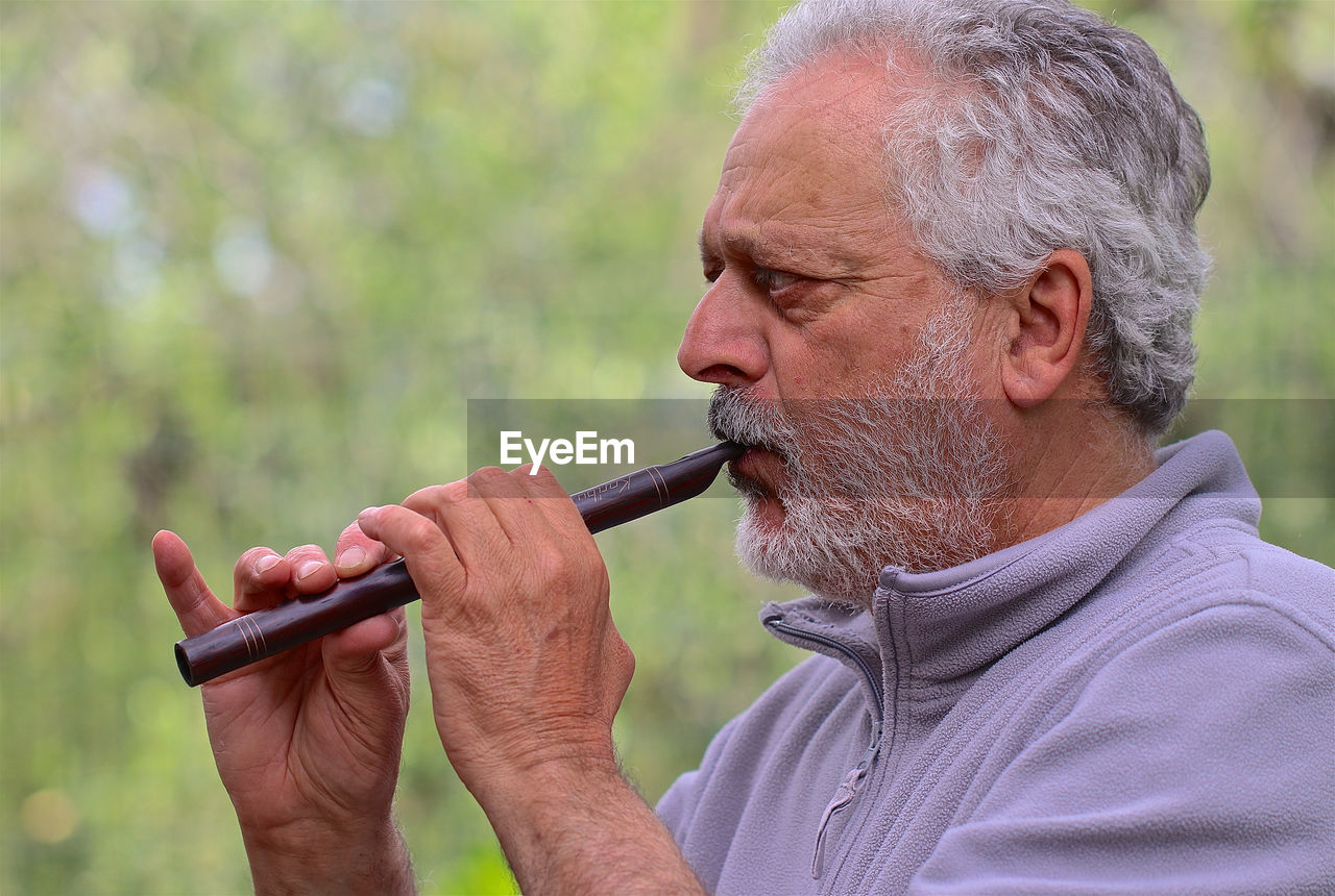 Man playing flute while standing outdoors