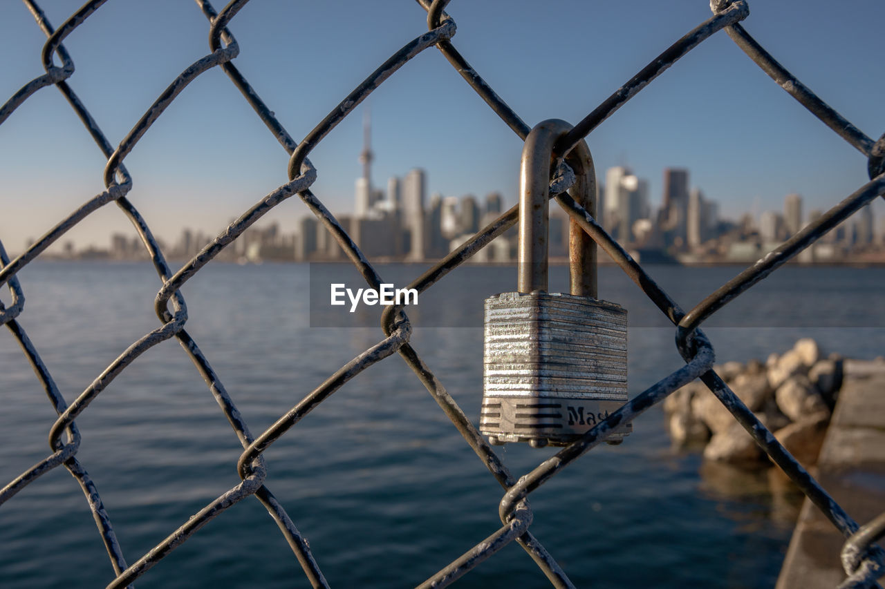 Close-up of chainlink fence against lake toronto 