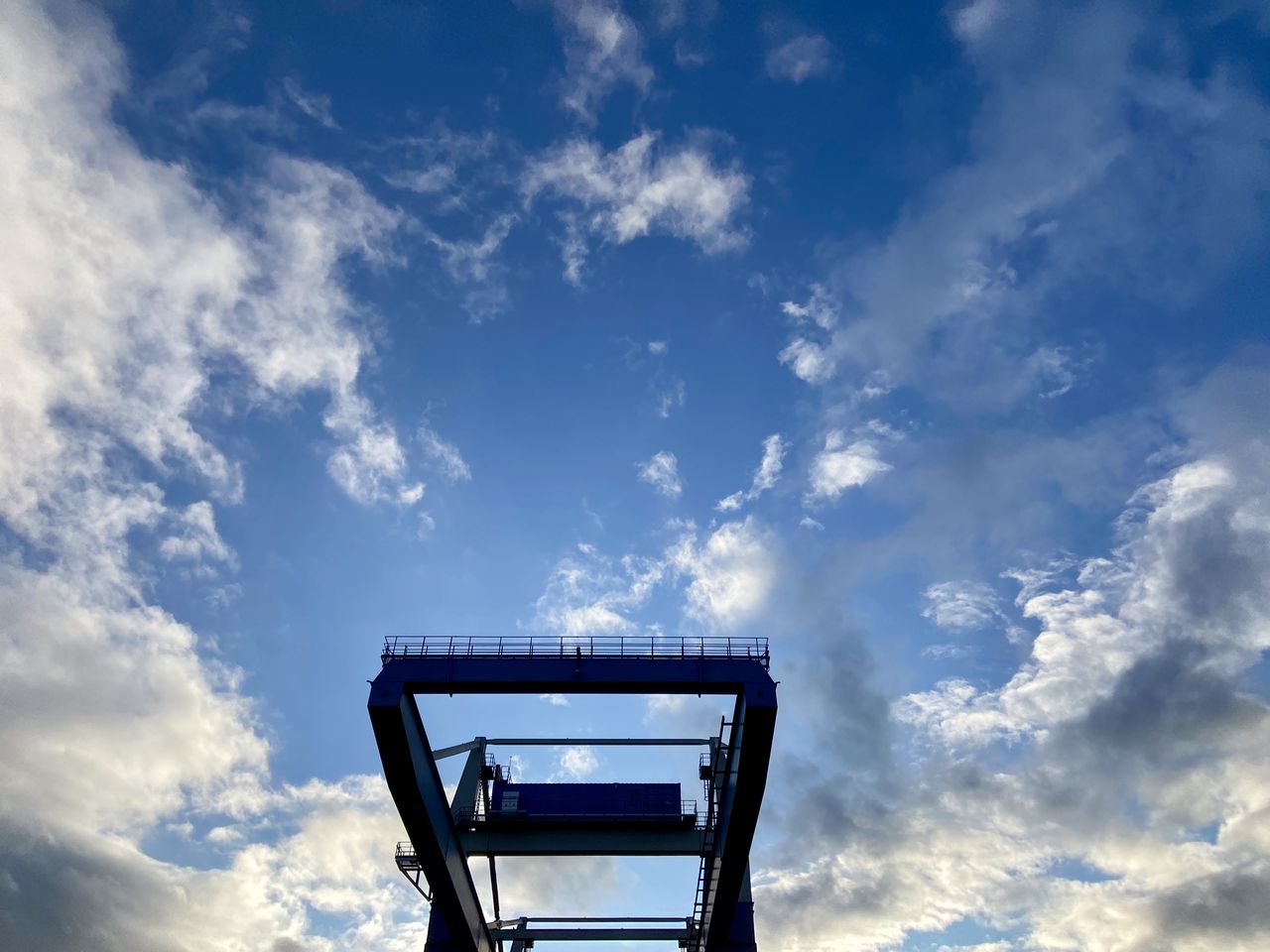 Low angle view of metallic structure of crane against blue sky