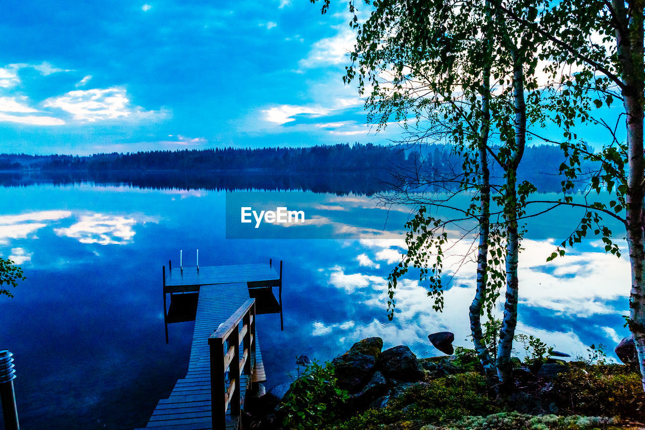 Jetty over river against cloudy sky