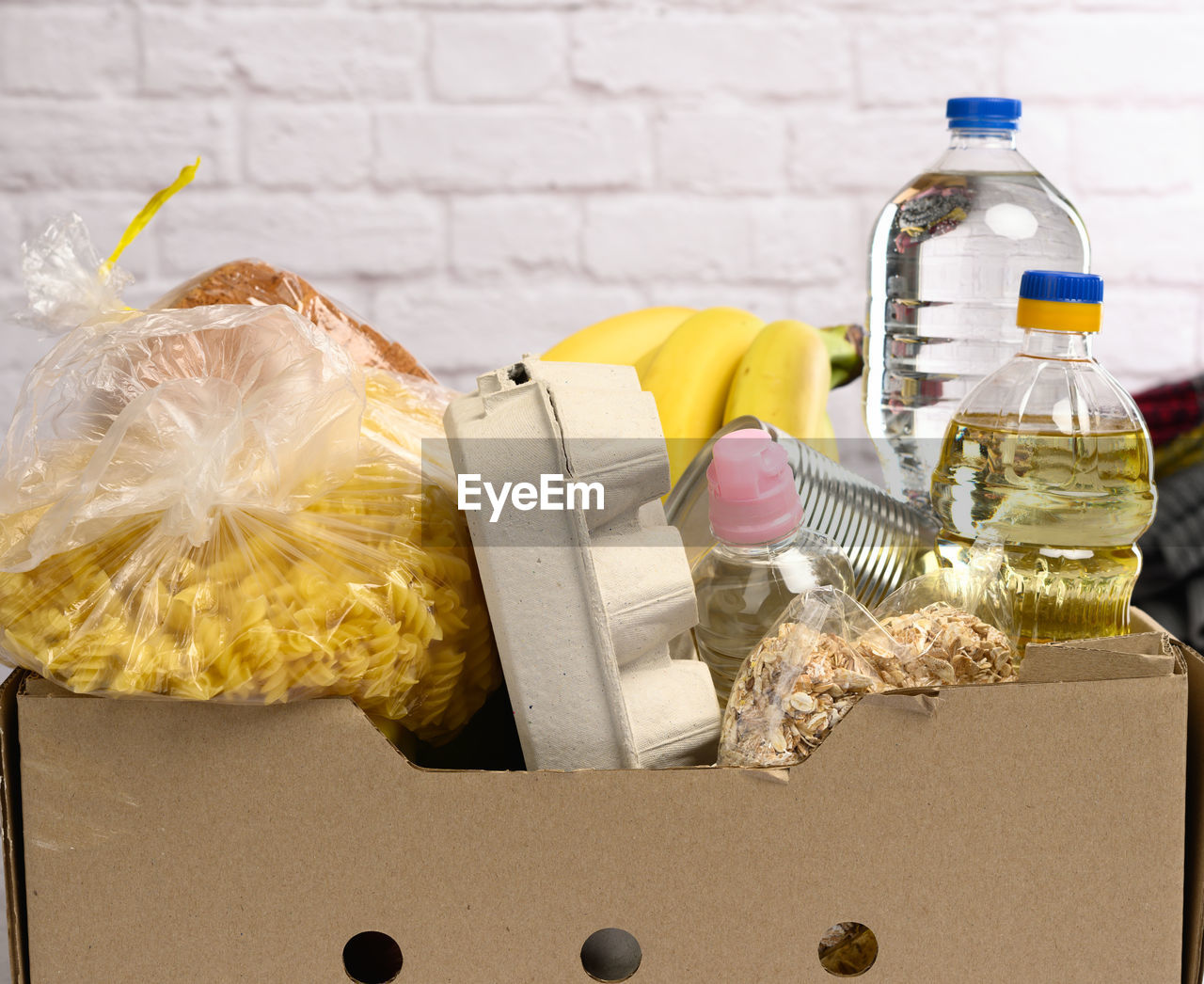 Cardboard box with various products, fruits, pasta, sunflower oil in a plastic bottle and pres