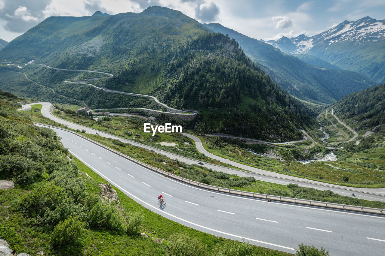 Aerial view of man riding bicycle on road amidst mountains against sky
