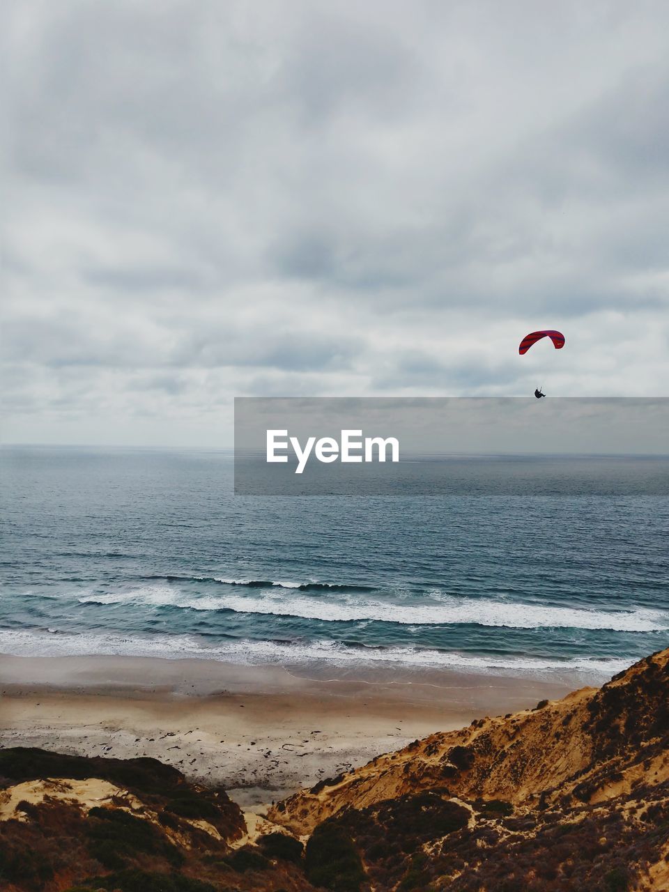 Scenic view of a paraglider floating in the sky above the cliffs and sea 