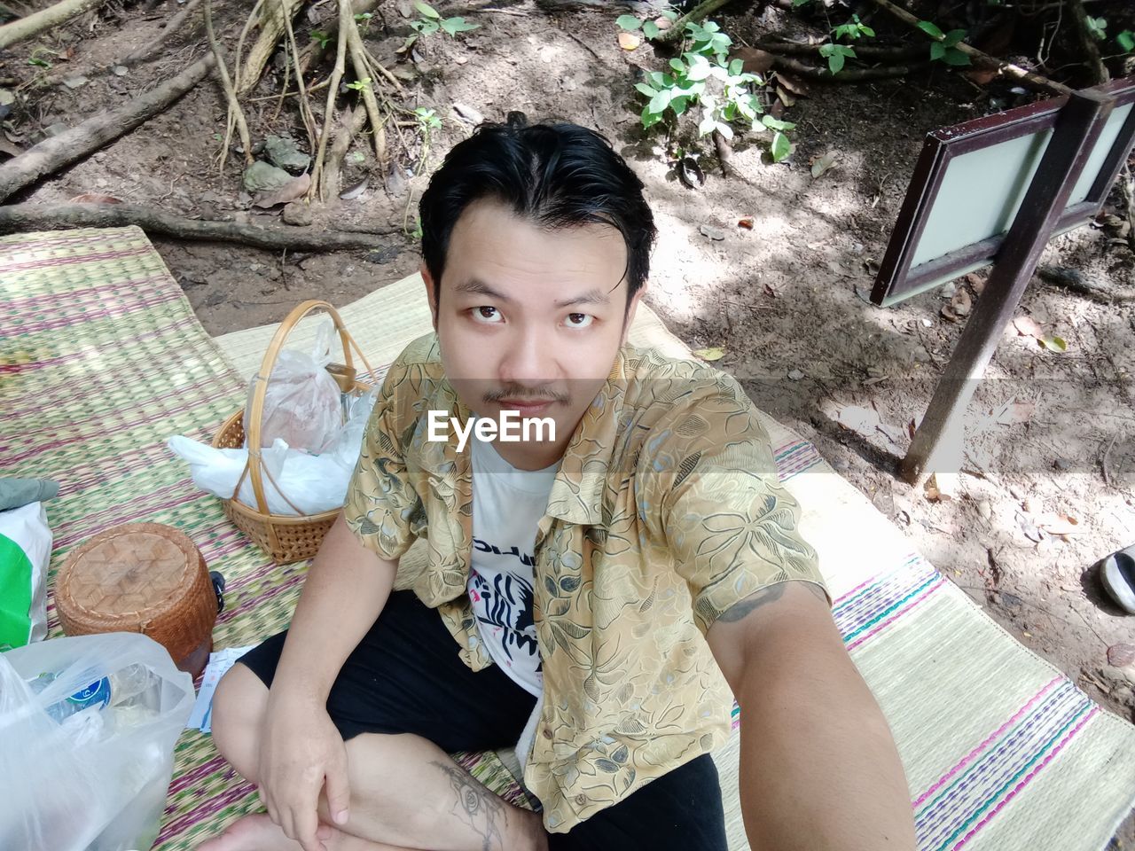 Portrait of smiling man sitting on mat at picnic