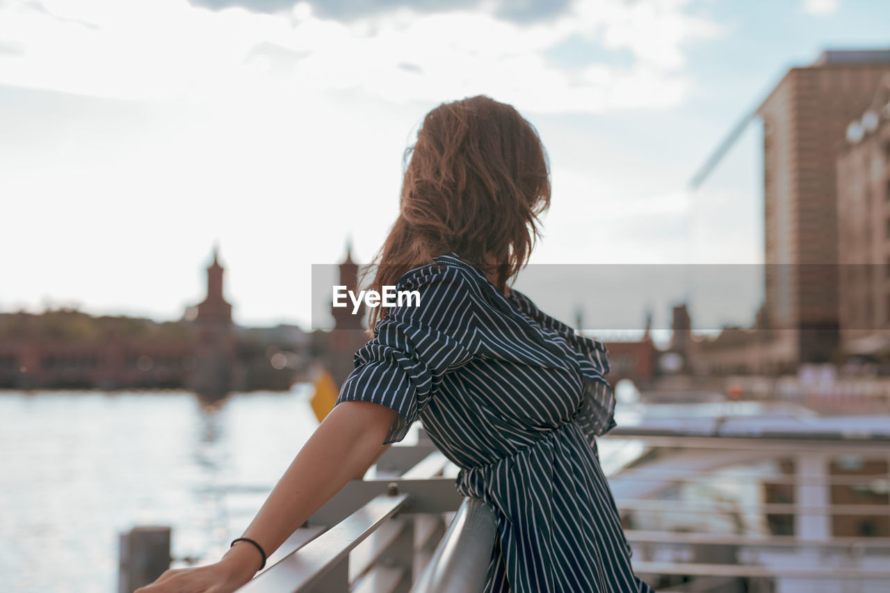 Side view of woman standing by railing in city