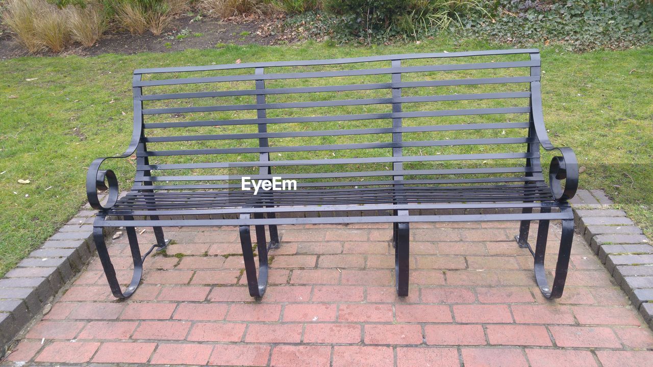 HIGH ANGLE VIEW OF BENCH ON FOOTPATH IN PARK