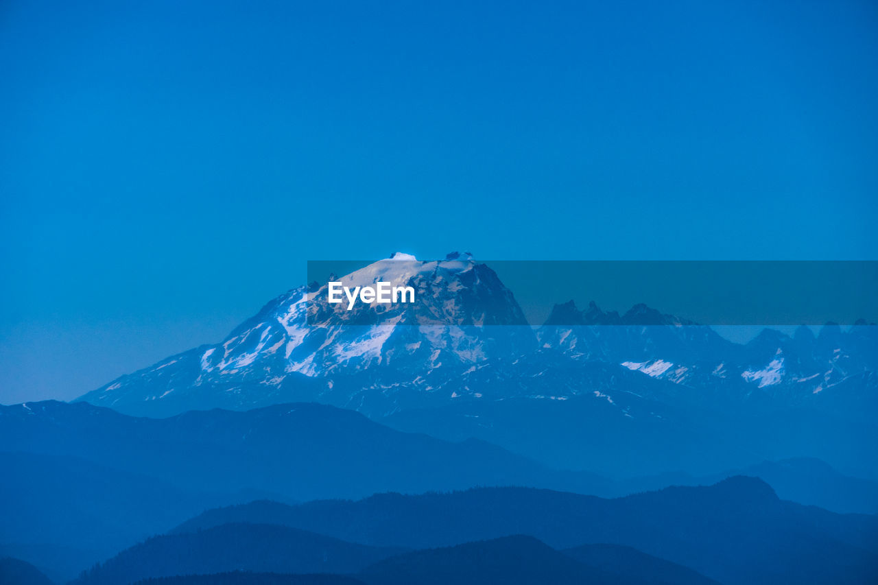 Scenic view of snowcapped mountains against blue sky