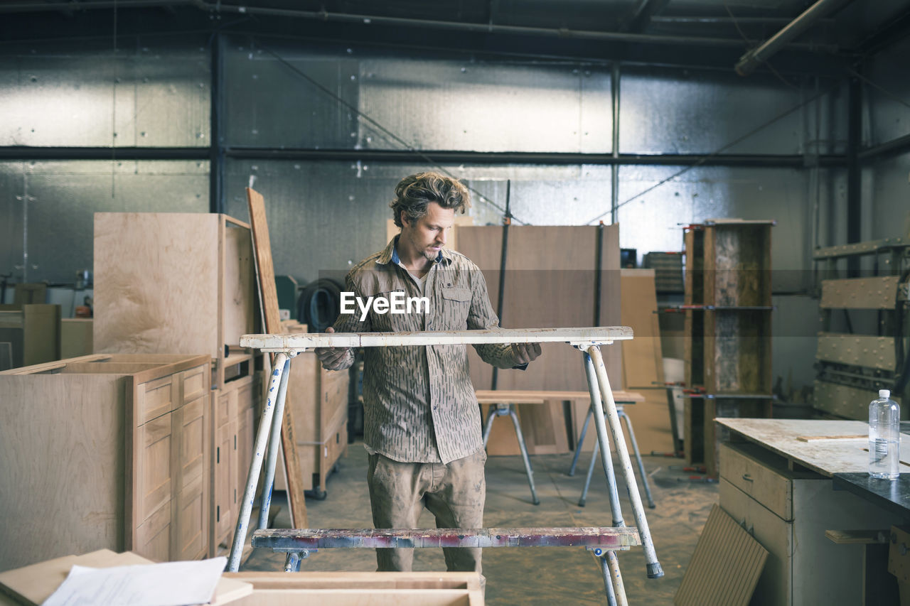 Carpenter holding table while working at workshop