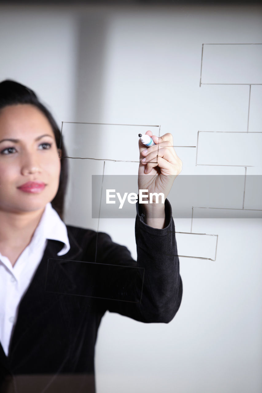 Businesswoman writing on glass board