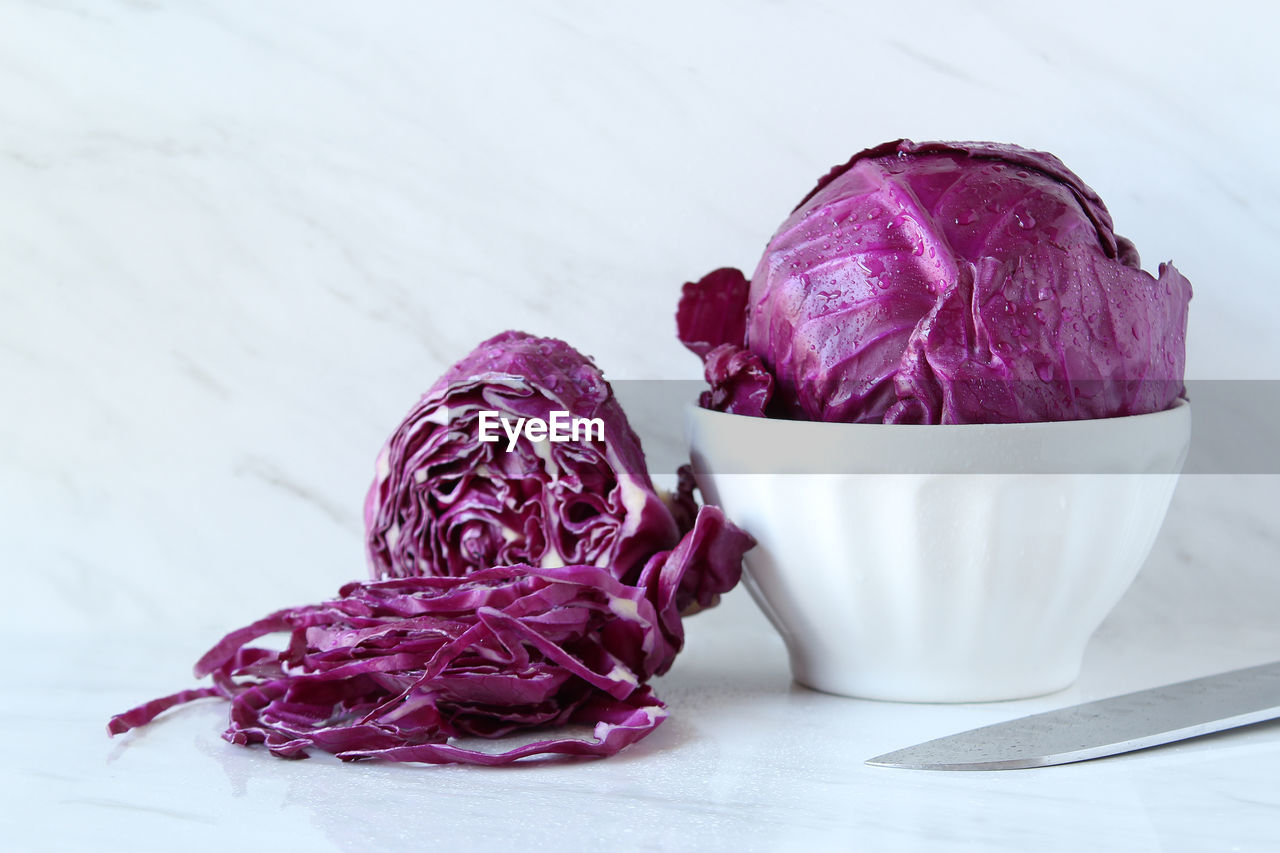 Close-up of red cabbages with bowl on marble